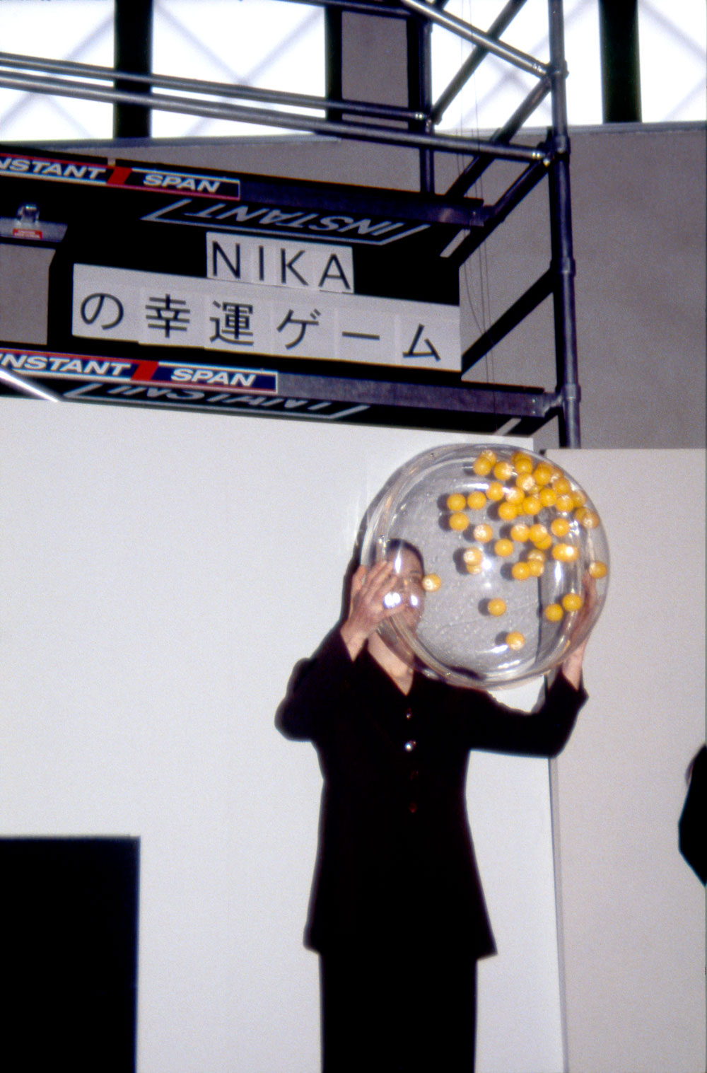 Art, artwork. A performance entitled "Nika's Game of Chance" by Nika Span / Nika Špan. Material: 49 numbered table tennis balls, a Plexiglas sphere, a fan, 20 copies of a lottery ticket, a female assistant. Exhibition: Academy Exchange, School of Art and Design, Seoul, Korea; Tokyo Geijutsu, Tokyo, Japan.